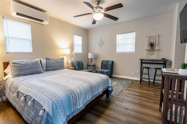 Living area with bed, chairs, dining table and smart TV.  