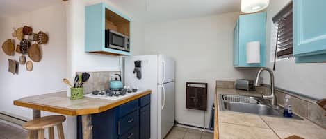 Cozy kitchen with full-size fridge and pull-down kitchen faucet.