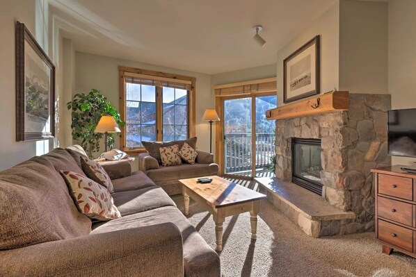 Cozy Living Room space with gas fireplace, pullout bed, and sliding glass door to a furnished patio overlooking the mountain!