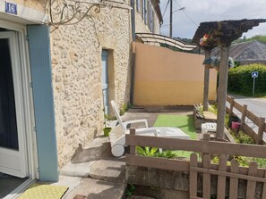 Terrasse plein sud en façade de la maison, donnant sur la rue face à la rivière