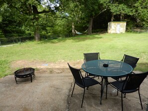 Fenced-in backyard, patio set, firepit, hammock, forest setting
