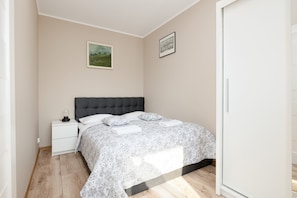 A cozy bedroom with a double bed covered in patterned bedding and simple decor.