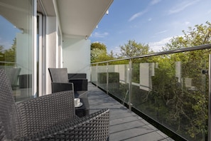 A spacious balcony with outdoor furniture and a view of the surrounding greenery.
