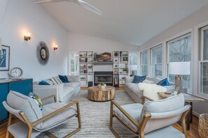 Gather in the inviting living room, complete with a fireplace, comfortable seating, and large windows that flood the space with natural light.