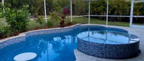 Swimming pool and hot tub in screened enclosure