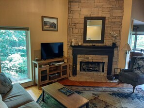 Main living room with floor to ceiling stone gas fireplace.