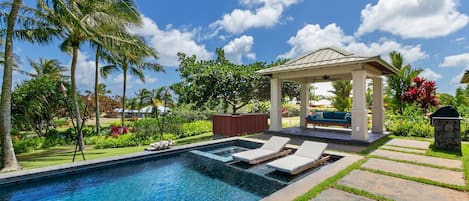 Lush landscaping adds privacy to the pool area with covered cabana and baja shelf lounge chairs