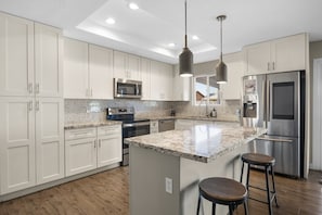 Amazing kitchen with brand new stainless steel appliances, kitchen island and dining table.