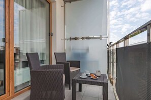 A balcony with outdoor seating, offering a view of the surrounding neighborhood.