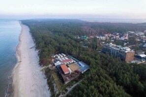 A stunning drone shot showcasing the surrounding forest, roads, and a cluster of buildings in a tranquil setting.