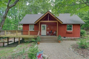 This cute cabin features an upper and lower deck, plus a low patio and a pond further down.