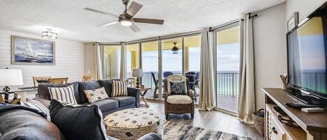 Spacious living room with plenty of seating and large flat screen TV, beautiful view of the Gulf with balcony access