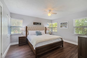 Master King bedroom with TV in room and adjacent bathroom in hallway.