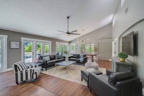 Spacious living room with ample seating and lovely view of the pool and backyard.