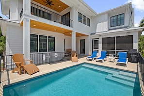 Pool and pool deck with lounge chairs and grill.