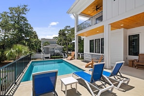 Pool and pool deck with lounge chairs, grill and glider.