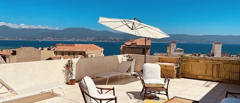 terrasse avec transats, chaises longues, fauteuils, table à manger, 2 parasols