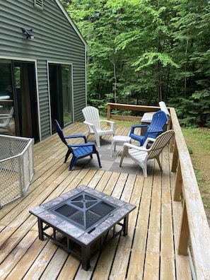 outdoor deck with fire pit and seating. Surrounded by trees and small back yard