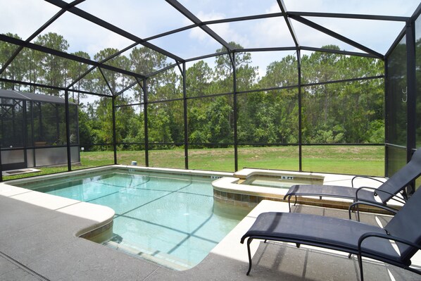 West-facing pool deck with four loungers, arm chairs and shaded dining area