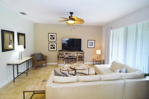 Lounge with L-shaped leather sofa, Smart TV and ceiling fan, pool views