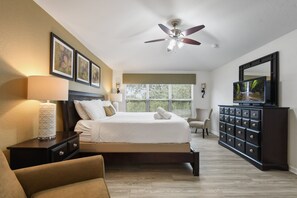 Spacious master suite with king bed, elegant decor, flat-screen TV, and natural light.
