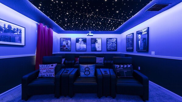 Immersive home theater with star ceiling, recliners, and classic movie decor.