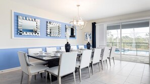 Elegant dining room with pool view, modern decor, and seating for large groups.