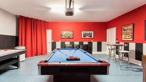 Vibrant game room with pool, air hockey, and comic-themed decor for fun nights.
