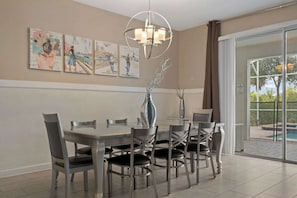 Elegant dining area with seating for ten, modern lighting, and pool views.

