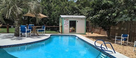 lap pool with fenced yard and palm tree