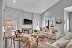 The light-filled living room is open to the kitchen and dining areas and features a large smart TV