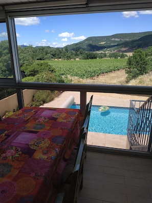 véranda avec vue sur piscine, vignes et collines