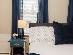 This bedroom features a spacious Queen-size bed with windows that allow natural light to fill the room, creating a cozy and inviting atmosphere.