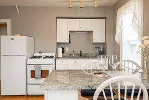 This is a spacious kitchen featuring a bar counter, equipped with all the necessary appliances and utensils for your cooking needs.