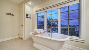 Primary bedroom bathroom soaking tub with triple windows that bring the skyline in.