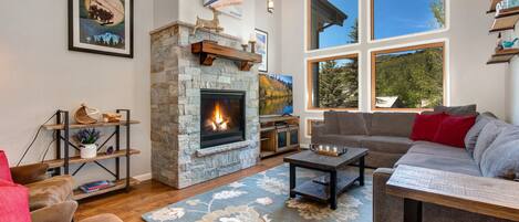 Living Room with Samsung smart tv, plush sectional sofa, gas fireplace, floor to ceiling windows, and separate sitting area with two leather armchairs