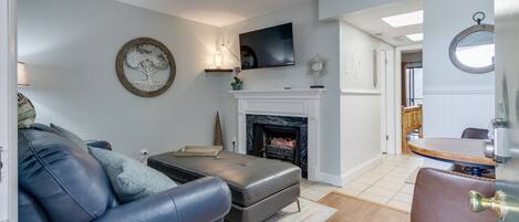 New leather sofa and ottoman in the living room.  It has an electric fireplace.