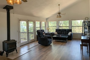 Large lounge with reclining sofas, fireplace, piano, cabinet drawers with games.
