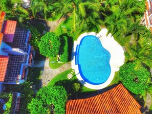 The community pool is surrounded by tropical landscaping.