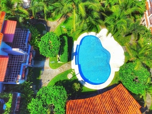 The community pool is surrounded by tropical landscaping.