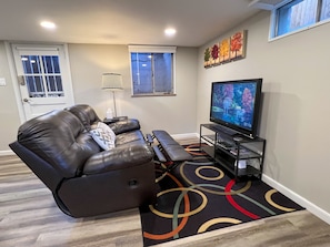 The living room area features a reclining leather sofa and a Roku controlled tv.