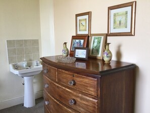 Bedroom 1 has a wash basin, large chest of drawers and a wardrobe