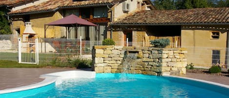 La piscine et sa cascade devant le gîte.