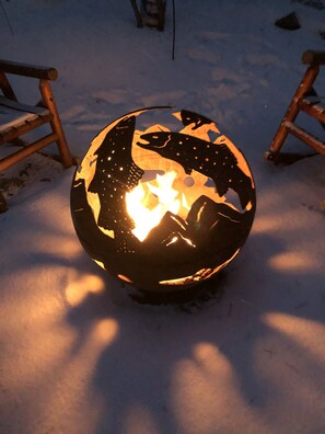 Fire pit is a steel ball piece of art with trout & mountains, propane powered. 