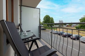 Umeblowany balkon z widokiem na zieloną okolicę. 