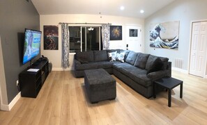 Large living area with sectional couch ottoman and 70” TV.  