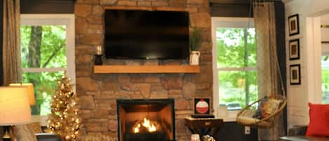 Living room overlooks Autumn Lake, custom stone gas fireplace, exposed trusses
