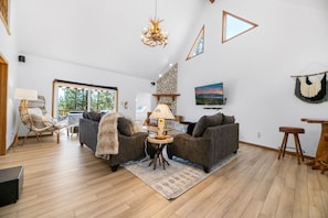 Living Room with Rock Fireplace - Spacious vaulted ceiling open to back deck, hot tub and lake views from top deck