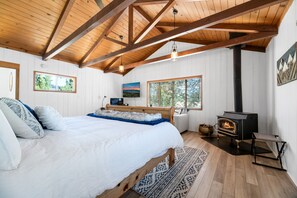 Master Bedroom. - KING Bed with attached En-suite BATHROOM and TWIN PULLOUT SOFA BED -  Master bath with LARGE fully remodeled shower. Vaulted ceiling with gorgeous truss beams, free-standing wood burning fireplace keeps room cozy, Executive Remote-Work Office set-up. Access to large lower Deck.