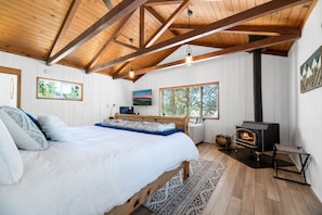 Master Bedroom. - KING Bed with attached En-suite BATHROOM and TWIN PULLOUT SOFA BED - Master bath with LARGE fully remodeled shower. Vaulted ceiling with gorgeous truss beams, free-standing wood burning fireplace keeps room cozy, Executive Remote-Work Office set-up. Access to large lower Deck.